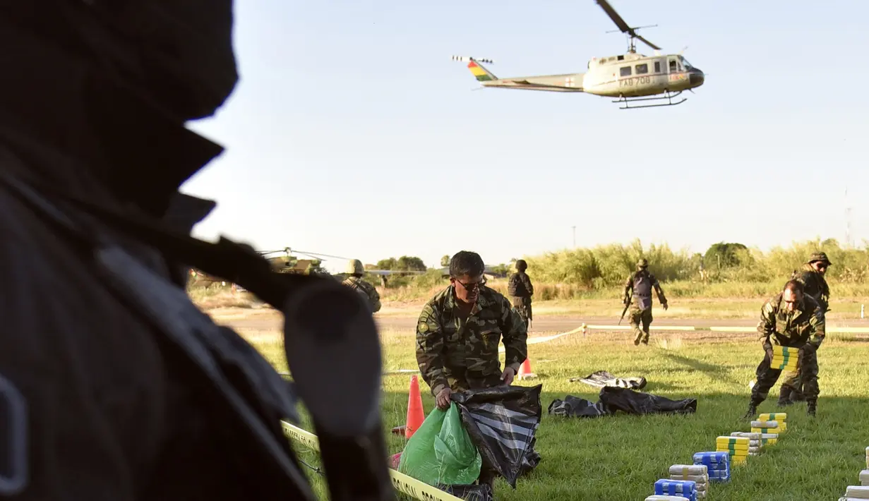 Petugas berjaga di dekat tumpukan satu ton kokain dalam paket yang disita di lokasi Baures saat jumpa pers di Trinidad, El Beni, Bolivia (19/7). Kabarnya obat terlarang tersebut akan dikirim ke Brasil. (AFP Photo/Ar/Aizar Raldes)