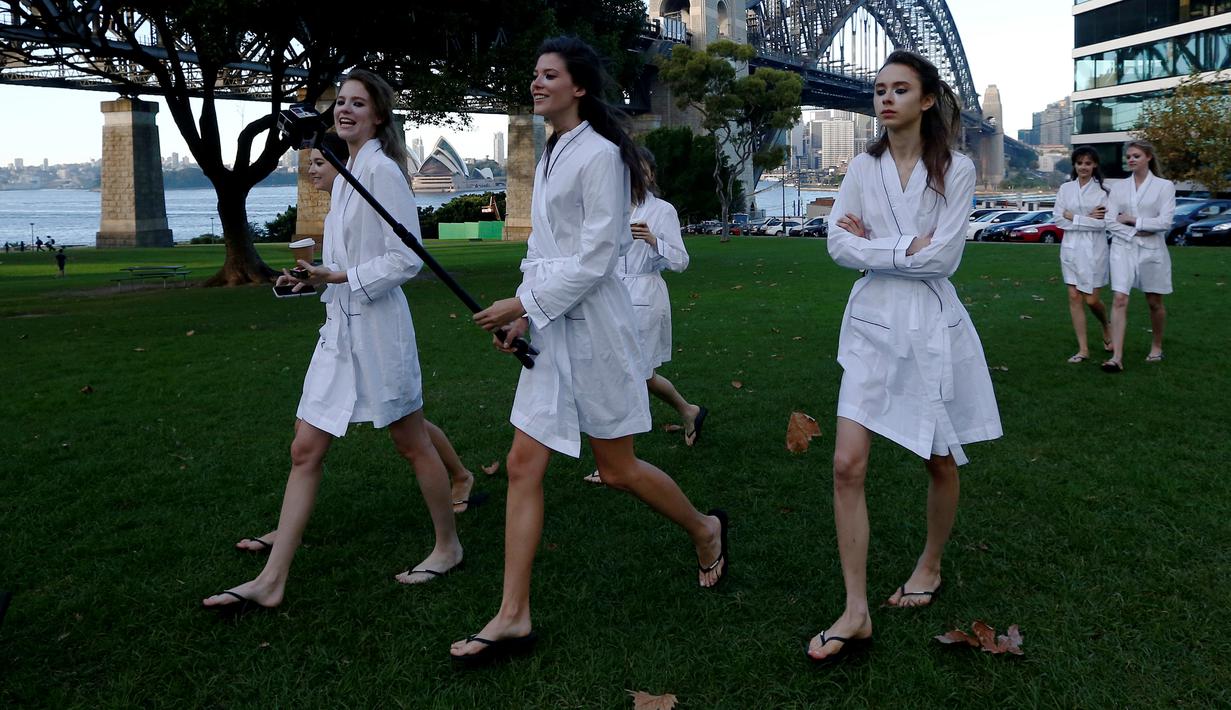 Sejumlah model berjalan dengan tongkat selfienyadi samping jembatan Sydney Harbour Bridge dalam perjalanan ke lokasi catwalk acara Manning Cartell di Australia Fashion Week, 17 Mei 2016. (REUTERS/Jason Reed)