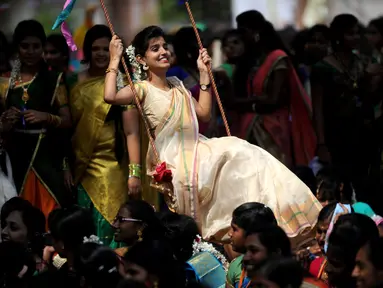 Wanita India bermain ayunan saat festival panen Tamil di perguruan tinggi di Chennai, India (11/1).  Perayaan ini sebagai simbol terima kasih warga kepada alam yang telah memberi hasil panen yang melimpah. (AFP Photo/Arun Sankar)