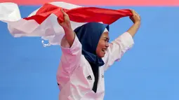 Atlet taekwondo, Defia Rosmaniar, melakukan selebrasi usai berhasil meriah medali emas pertama untuk Indoensia di Asian Games 2018 di JCC, Jakarta, Minggu (19/8/2018). (Bola.com/Peksi Cahyo)