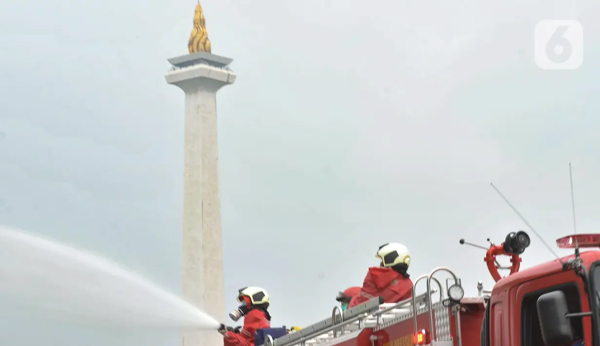 Petugas pemadam kebarakan menyemprotkan cairan disinfektan di kompleks Monumen Nasional (Monas), Jakarta, Senin (30/3/2020). Penyemprotan disinfektan ini dilakukan guna memutus rantai penyebaran virus Corona atau Covid-19 di pusat kota. (merdeka.com/Iqbal S. Nugroho)