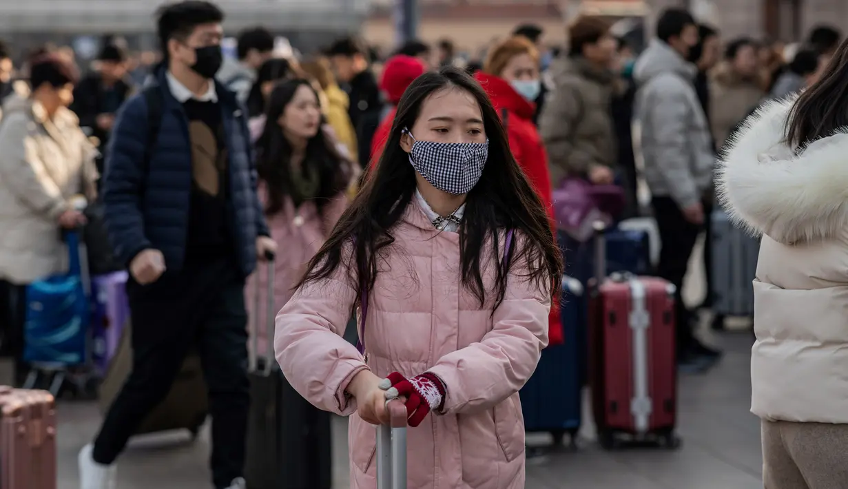Orang-orang mengenakan masker penutup mulut setibanya di stasiun kereta api Beijing untuk mudik Tahun Baru Imlek pada Selasa (21/1/2020). Virus mirip SARS yang menyebar ke seluruh wilayah China dan mencapai tiga negara Asia ternyata dapat menular dari satu orang ke orang lain. (NICOLAS ASFOURI/AFP)