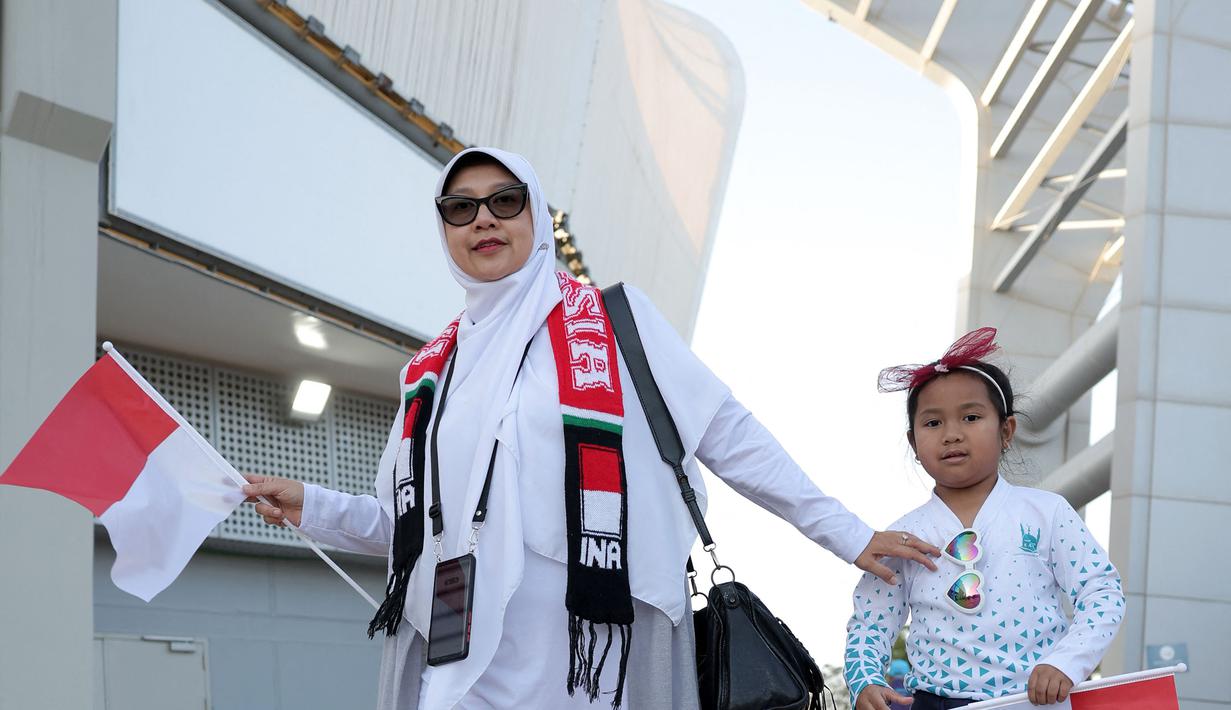 Seorang suporter wanita Indonesia bersama sang anak tiba di stadion sebelum dimulainya laga kedua Grup D Piala Asia 2023 antara Timnas Indonesia menghadapi Vietnam di Abdullah Bin Khalifa Stadium, Doha, Qatar, Jumat (19/1/2024). (AFP/Karim Jaafar)