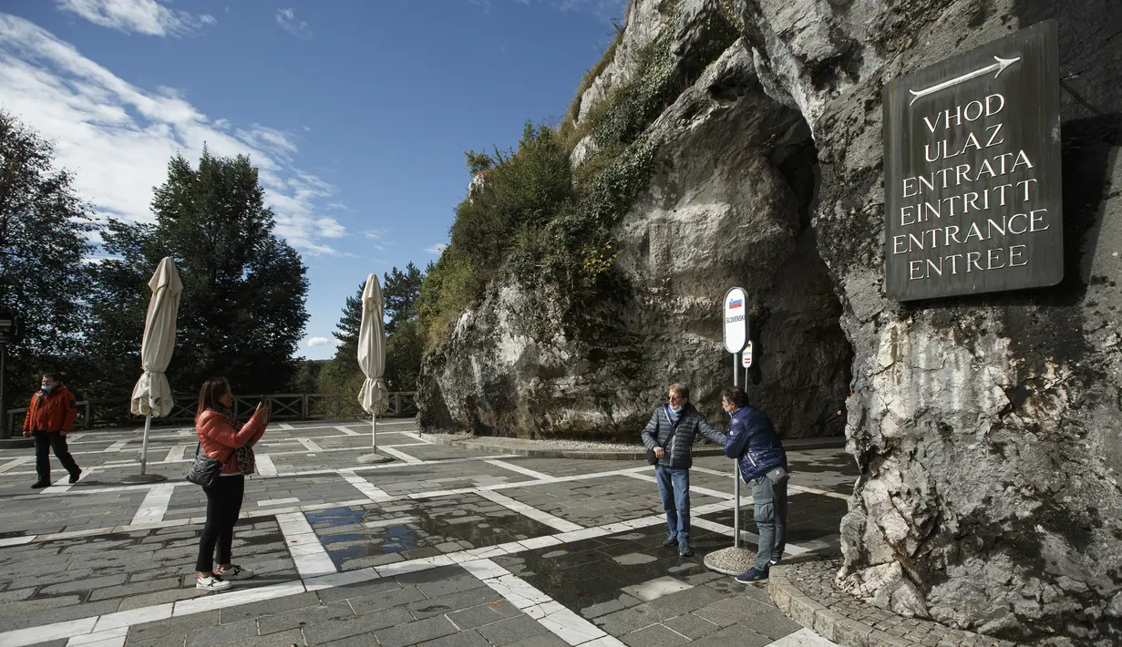 Sejumlah pengunjung berpose untuk difoto di depan pintu masuk Gua Postojna, Slovenia, 29 September 2020. Gua Postojna merupakan salah satu objek wisata alam terkenal di Slovenia. (Xinhua/Zeljko Stevanic)