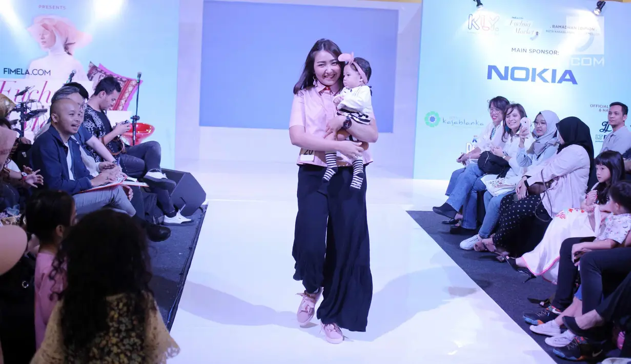 Seorang ibu bersama anaknya berjalan di atas catwalk saat mengikuti fashion show Fabalous Mom and Kids 2018 di Fimela Fuchsia Market 2018 di Kota Kasablanka, Jakarta (27/5). (Liputan6.com/Faizal Fanani)