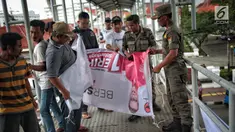 Petugas Satpol PP menertibkan alat peraga kampanye (APK) di jembatan penyeberangan orang (JPO) kawasan Gambir, Jakarta, Sabtu  (22/12). Penertiban itu dilakukan karena melanggar aturan pemasangan dari komisi pemilihan umum. (Liputan6.com/Faizal Fanani)