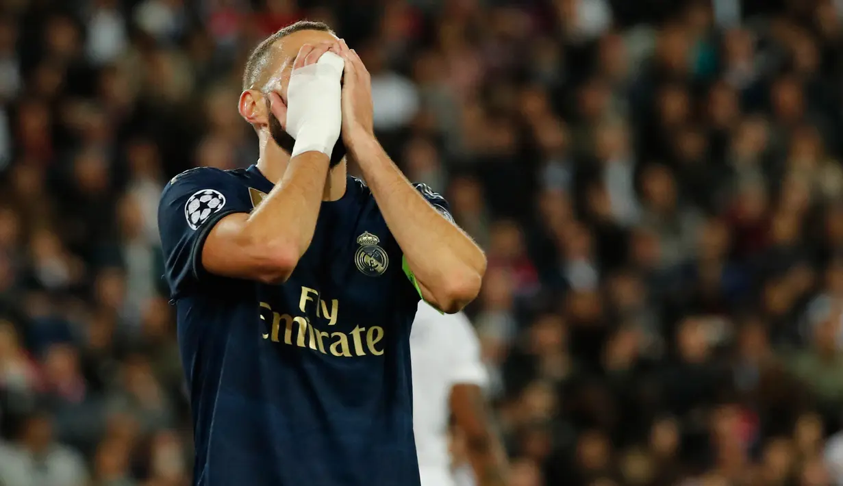 Penyerang Real Madrid, Karim Benzema menutup wajahnya dengan tangan setelah kehilangan peluang mencetak gol ke gawang Paris Saint-Germain (PSG) pada laga Grup A Liga Champions di Parc des Princes, Rabu (18/9/2019). Real Madrid kalah telak dengan skor 0-3. (AP Photo/Francois Mori)