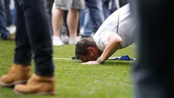 Seorang supporter Tottenham Hotspur mencium rumput lapangan usai pertandigan di Liga Inggris di stadion White Hart Lane, London, (14/5). Biaya pembangunan stadion tersebut mencapai sekitar Rp 13 triliun rupiah. (AP/Frank Augstein)