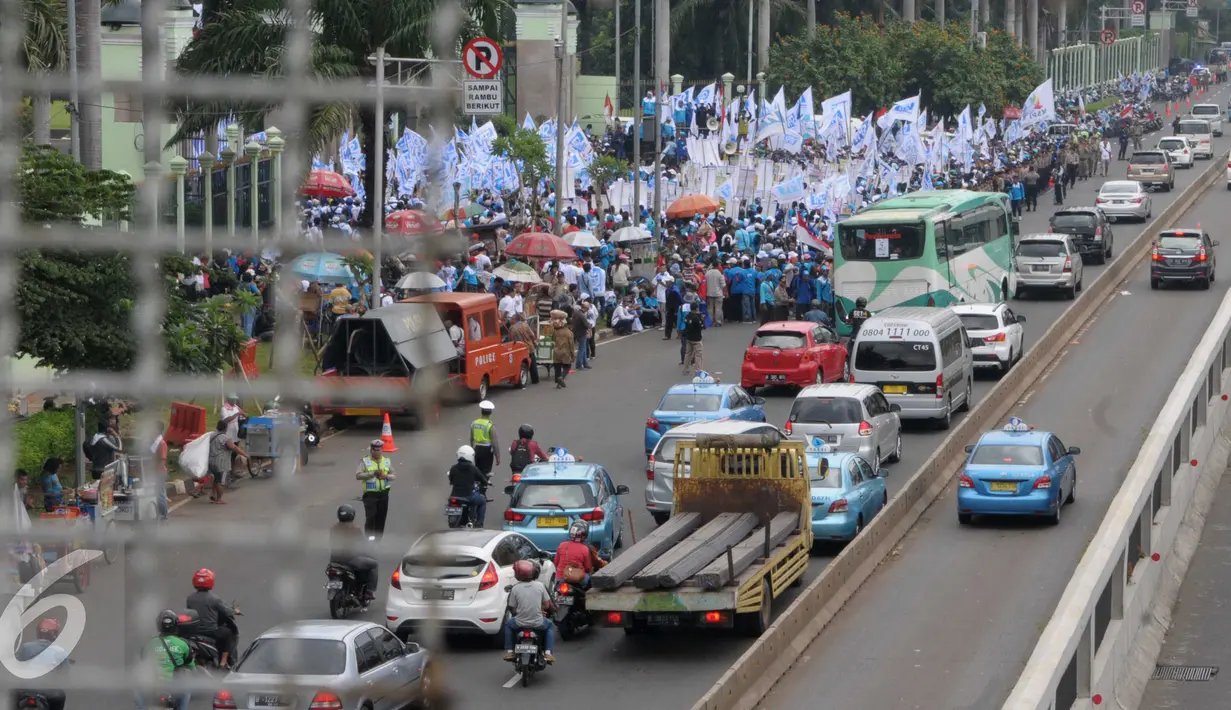 Aksi buruh di depan Gedung DPR RI menyebabkan kemacetan, Jakarta, Minggu (1/5). Petugas Kepolisian mengatur lalu lintas agar tidak terjadi kemacetan yang panjang. (Liputan6.com/Helmi Afandi)