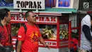 Dua pria berjalan melewati pedagang ketoprak yang menjajakan dagangannya di sisi jalan sekitar kawasan Patung Kuda Jakarta, Rabu (5/1/2019). Mereka mencoba peruntungan saat para buruh melakukan aksi perayaan Hari Buruh International atau May Day. (Liputan6.com/Helmi Fithriansyah)