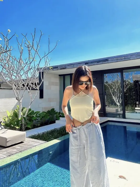 Perempuan kelahiran 1994 ini juga mengenakan atasan high neck sleeves asimetris warna kuning yang dipadukan spaghetti strap warna abu-abu serasi dengan celana panjangnya. (@andiannsyah)