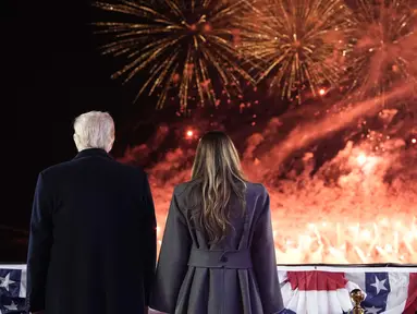 Presiden terpilih Amerika Serikat (AS) Donald Trump dan istrinya Melania Trump menyaksikan kembang api saat resepsi di Trump National Golf Club Washington DC, Sterling, Virginia, pada 18 Januari 2025. (Alex Brandon/POOL/AFP)