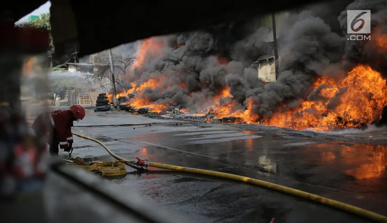 Petugas pemadam kebakaran berusaha memadamkan api yang melalap gudang di Jalan Kampung Bandan, Ancol, Jakarta Utara, Kamis (5/7). Gudang yang terbakar berisikan ban kontainer. (Liputan6.com/Faizal Fanani)