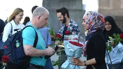 Seorang muslim membagikan bunga mawar disertai sebuah pesan kepada pejalan kaki di London Bridge, Minggu (11/6). Muslim Inggris membagikan ratusan mawar sebagai bentuk solidaritas menyusul teror London yang terjadi pekan lalu. (David Mirzoeff/PA via AP)