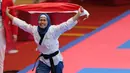 Atlet taekwondo, Defia Rosmaniar, melakukan selebrasi usai berhasil meriah medali emas pertama untuk Indoensia di Asian Games 2018 di JCC, Jakarta, Minggu (19/8/2018). (Bola.com/Peksi Cahyo)