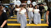 Sekelompok perempuan mengenakan gaun untuk menghadiri pernikahan menyeberangi jalan di tengah demo menentang undang-undang keadaan darurat, di Hong Kong, 12 Oktober 2019. (Source: AFP)