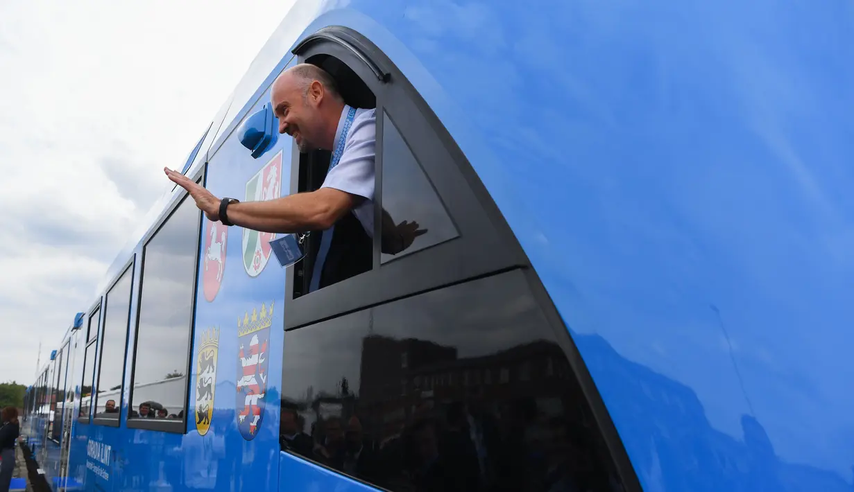 Seorang karyawan pembuat kereta Prancis, Alstom, melambai dari jendela setelah kedatangan kereta api bertenaga hidrogen pertama di stasiun untuk memulai layanan komersial di Bremervoerde, Jerman, , 16 September 2018. (AFP / Patrik STOLLARZ)