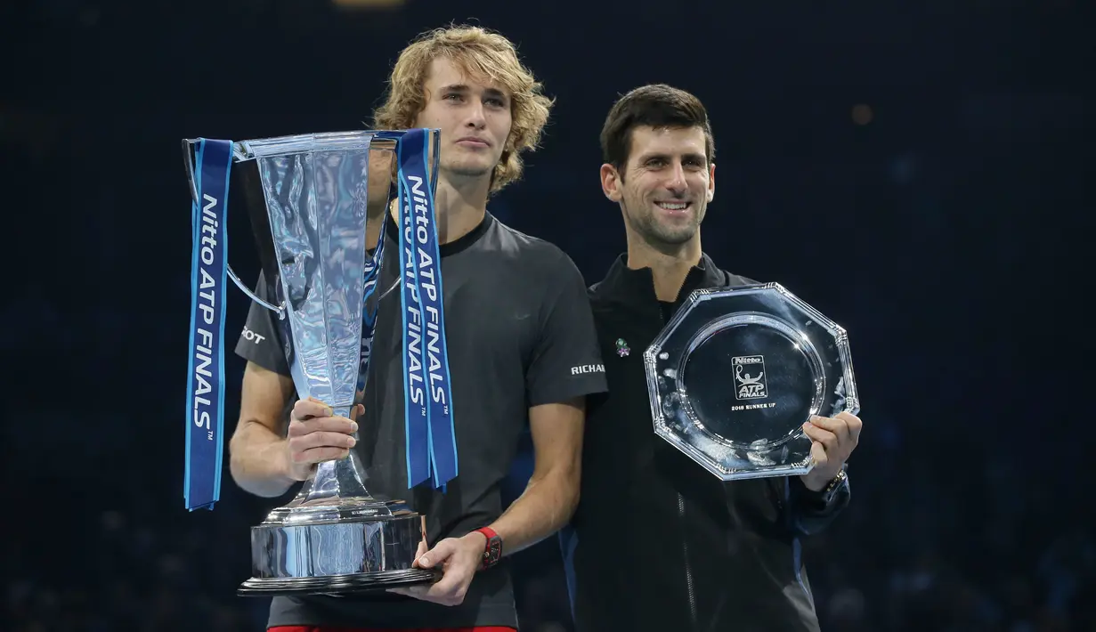 Petenis Jerman, Alexander Zverev memegang trofi pemenang dan Novak Djokovic dari Serbia memegang trofi runner-up setelah laga puncak ATP Finals 2018 di O2 Arena, London, Senin (19/11). (AP/Tim Ireland)