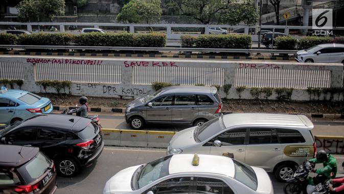 Pengendara melintasi dekat coret-coretan di sekitar Gedung DPR/MPR RI, Jakarta, Selasa (24/9/2019). Demonstrasi mahasiswa dari berbagai kampus yang menolak pengesahan RUU Kitab Undang-Undang Hukum Pidana(KUHP) tercoreng oleh aksi coret-coretan. (Liputan6.com/Faizal Fanani)