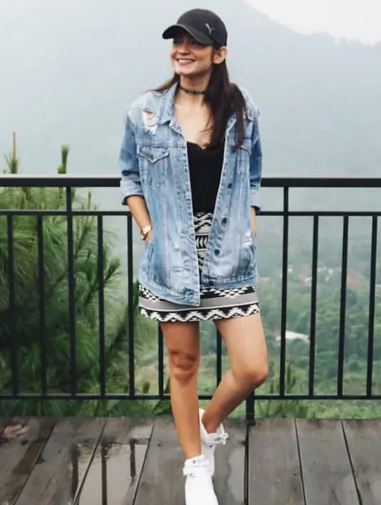 Enzy Storia tampil mengenakan oversize denim sebagai outer dipadukan inner hitam serasi dengan kalung choker yang saat itu tengah tren. Ia memadukannya dengan mini skirt hitam putih motif tribal dan mengenakan topi cap hitam.  [@enzystoria]