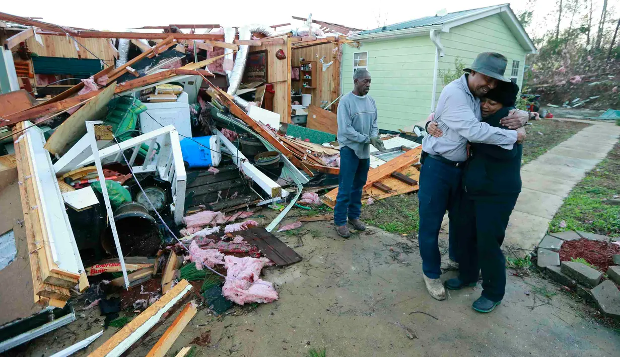 Phyllis Evans mendapat pelukan dari Harvey Payne setelah melihat kondisi rumahnya yang dihantam tornado di Holly Springs, Mississipi, Kamis (24/12). Badai tornado menerjang wilayah Amerika Serikat bagian selatan dan menewaskan 11 orang.  (REUTERS)