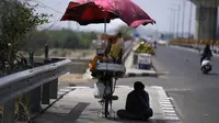 Seorang penjual makanan ringan duduk di bawah naungan dan menunggu pelanggan pada sore musim panas yang terik di Jammu, India, Kamis (19/5/2022). Banyak bagian barat laut dan tengah India terus mengalami kondisi gelombang panas. (AP Photo/Channi Anand)