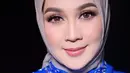 Dina Lorenza tak kalah memesona saat dipulas MUA @bennusorumba. Gaya riasannya berfokus pada riasan mata yang tajam dengan menggunakan eyeshadow coklat, bulu mata palsu yang bervolume dan lentik, serta alis yang dibentuk rapi.