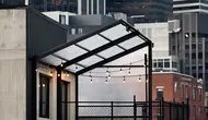 Desain rumah hunian industrial rooftop dengan atap transparan polikarbonat, pagar besi hitam, dinding semen ekspos, dan pencahayaan lampu string. (Liputan6.com/MetaAi)