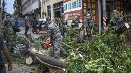 Beberapa tentara memotong batang pohon yang tumbang akibat hantaman Topan Rammasun yang memporak-porandakan kota Zhanjiang di provinsi Guangdong, (20/7/2014). (REUTERS/Stringer)
