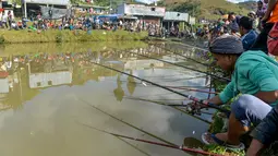Para peserta pria berkonsentrasi dengan kailnya pada kompetisi memancing di sebuah kolam dekat desa Weilei di Negara Bagian Meghalaya, timur laut India, Sabtu (21/9/2019). Ratusan peserta berpartisipasi dalam kompetisi yang memperebutkan sejumlah hadia tersebut. (DIPTENDU DUTTA / AFP)