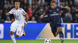 Penyerang PSG, Kylian Mbappe membawa bola dari kejaran gelandang Bayern Munchen Thiago Alcantara saat bertanding pada grup B Liga Champions di stadion Parc des Princes di Paris, Prancis (27/9). PSG menang telak 3-0 atas Munchen. (AFP Photo/Franck Fife)