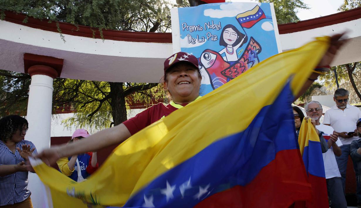 Nicolas Maduro ditangkap bersama istrinya, Cilia Flores, dalam sebuah operasi kejutan skala besar yang melibatkan serangan udara di beberapa titik penting di ibu kota Venezuela. Tampak dalam foto, seorang wanita mengibarkan bendera Venezuela saat merayakan penangkapan pemimpin mereka, Nicolas Maduro, di Monterrey, pada 3 Januari 2026. (Julio Cesar AGUILAR/AFP)