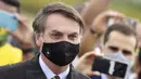 Presiden Brasil Jair Bolsonaro mengenakan masker saat meninggalkan kediaman resminya di istana Alvorada, Brasilia, Brasil, 25 Mei 2020. Kabar Bolsonaro terinfeksi COVID-19 pertama kali mencuat pada Senin 6 Juli 2020 malam. (AP Photo/Eraldo Peres, File)