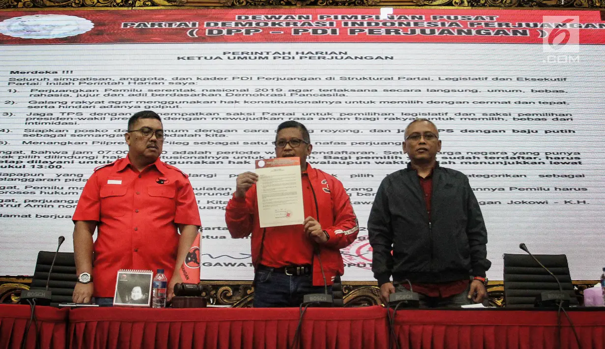 Sekjen DPP PDIP Hasto Kristiyanto (tengah) menunjukkan surat perintah Ketua Umum PDIP Megawati Soekarnoputri saat jumpa pers di Kantor DPP PDIP, Jakarta, Selasa (16/4). Megawati memberi lima perintah kepada kader dan jajarannya jelang pemungutan suara Pemilu 2019. (Liputan6.com/Faizal Fanani)