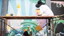 Seniman menyelesaikan pembuatan mural di kawasan Ragunan, Jakarta, Kamis (29/9/2022). Mural-mural tersebut menceritakan Jakarta sebagai Ibu Kota dengan berbagai latar belakang masyarakat yang mencintai alam. (Liputan6.com/Faizal Fanani)