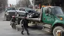 Pasukan keamanan Afghanistan memindahkan sebuah mobil yang hancur akibat terkena serangan bom bunuh diri di Kabul, Afghanistan (25/12). Bomber tersebut melancarkan serangannya saat para pekerja tiba di kantor mereka. (AP Photo / Rahmat Gul)