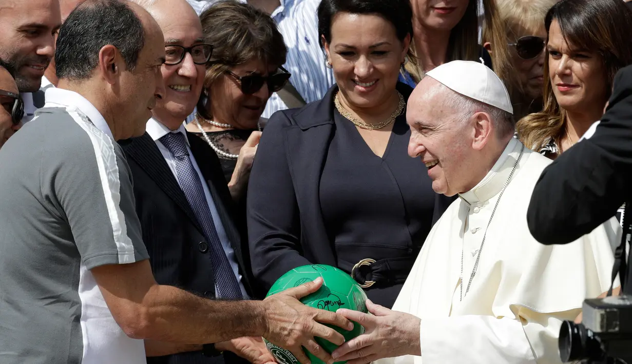 Paus Fransiskus menandatangani bola dari anggota tim sepak bola Chapecoense di Vatikan (30/8). Dalam kunjungan ke Italia, tim Chapecoense akan bertanding melawan AS Roma. (AP Photo / Andrew Medichini)