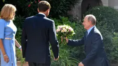 Presiden Rusia Vladimir Putin (kanan) berlutut memberi bunga kepada istri Presiden Prancis Emmanuel Macron (tengah), Brigitte Macron (kiri) di Benteng Bregancon, Bormes-les-Mimosas, Prancis, Senin (19/8/2019). Putin diketahui kerap memberi bunga kepada wanita. (Gerard Julien, Pool via AP)