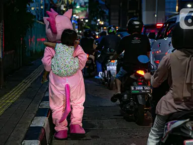 Warkuatno (41) bersama anak sulungnya, Bunga (9) berjalan kaki di pinggir Jalan Raya Fatmawati, Cilandak, Jakarta, Rabu (6/1/2021). Warkuatno harus memutar otak demi bisa bertahan hidup usai kehilangan pekerjaannya. (Liputan6.com/Faizal Fanani)