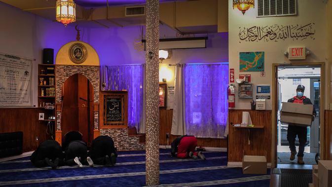 Sukarelawan membawa bahan makanan untuk yang membutuhkan saat anggota Muslim Giving Back lainnya beribadah di Pusat Komunitas Muslim di lingkungan Bay Ridge, Brooklyn, New York, pada 27 April 2020. Kegiatan komunitas Muslim tersebut berlangsung selama Ramadan. (AP Photo/Wong Maye-E)