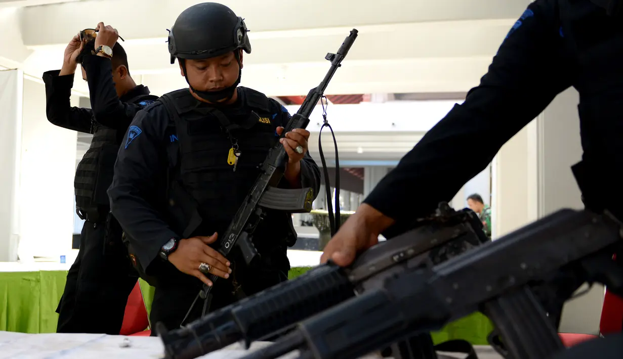 Anggota kepolisian menyiapkan senjata mereka untuk berpatroli di Bandara Ngurah Rai, Denpasar, Jumat (15/1). Pasca serangan di Sarinah, Jakarta, pengelola Bandara Internasional I Gusti Ngurah Rai, Bali perketat pengamanan. (AFP PHOTO/Sonny Tumbelaka)