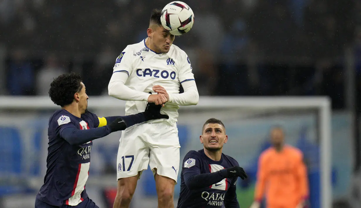 Penyerang Marseille Cengiz Under berebut bola dengan pemain Paris Saint-Germain (PSG) Marquinhos dan Marco Verratti dalam laga pekan ke-25 Liga Prancis 2022-2023, di Stadion Velodrome pada Senin (27/2/2023) dini hari WIB. Kylian Mbappe mencetak dua gol (25', 55') dan Lionel Messi menyumbang satu gol (29') untuk menyempurnakan kemenangan PSG. (AP Photo/Daniel Cole)