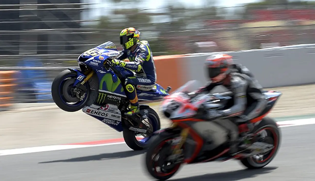 Valentino Rossi (kiri) melakukan aksi wheelie atau mengangkat ban depan saat menyalip Marco Melandri saat sesi latihan di sirkuit Barcelona-Catalunya pada GP Catalunya. (AFP/JOSEP LAGO)