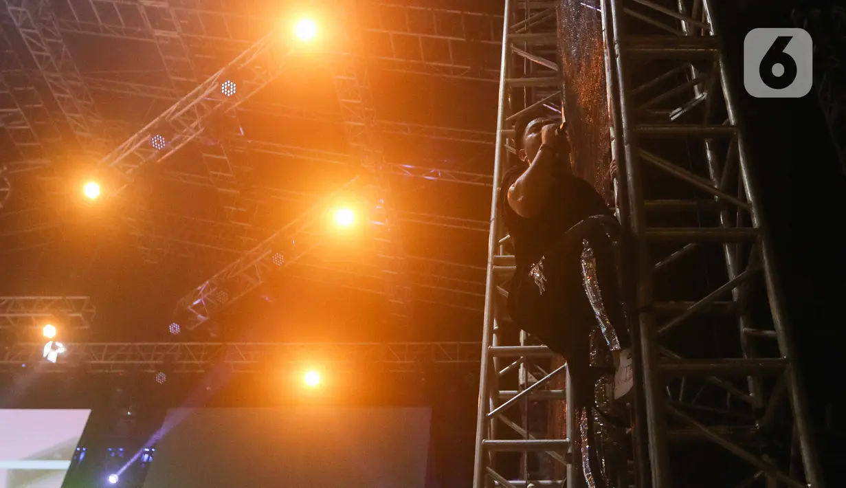 Penyanyi Nassar memanjat tiang panggung saat tampil memeriahkan acara Pestapora di Gambir Expo, Kemayoran, Jakarta, Minggu (25/9/2022). Nassar tampil menghibur dengan membawakan lagu seperti 'Kereta Malam', 'Seperti Mati Lampu', dan Sekuntum 'Mawar Merah'. (Liputan6.com/Herman Zakharia)