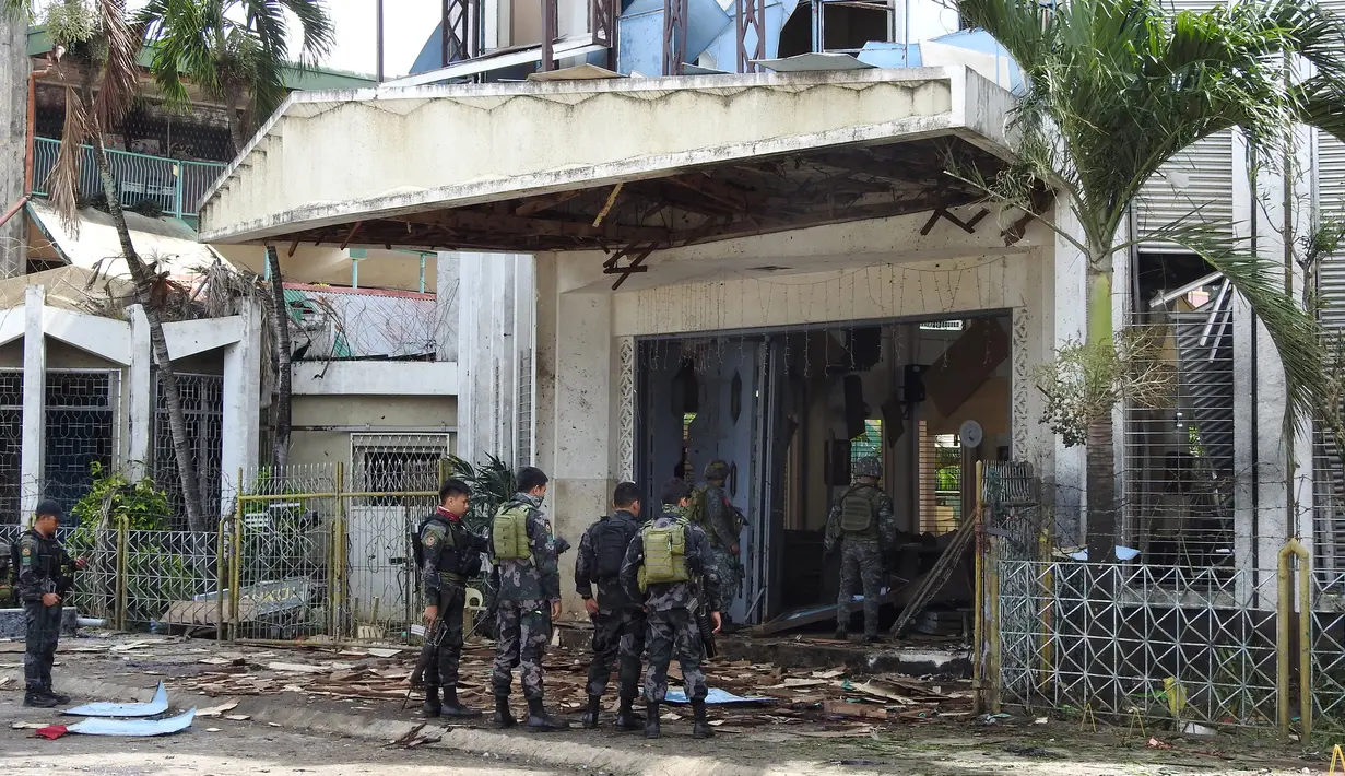 Polisi dan tentara berjaga pasca ledakan bom di Gereja Katolik Jolo, Filipina Selatan, Minggu (27/1). Dua bom meledak, Sedikitnya 27 orang tewas dan 57 orang lainnya mengalami luka. (Nickee Butlangan/AFP)