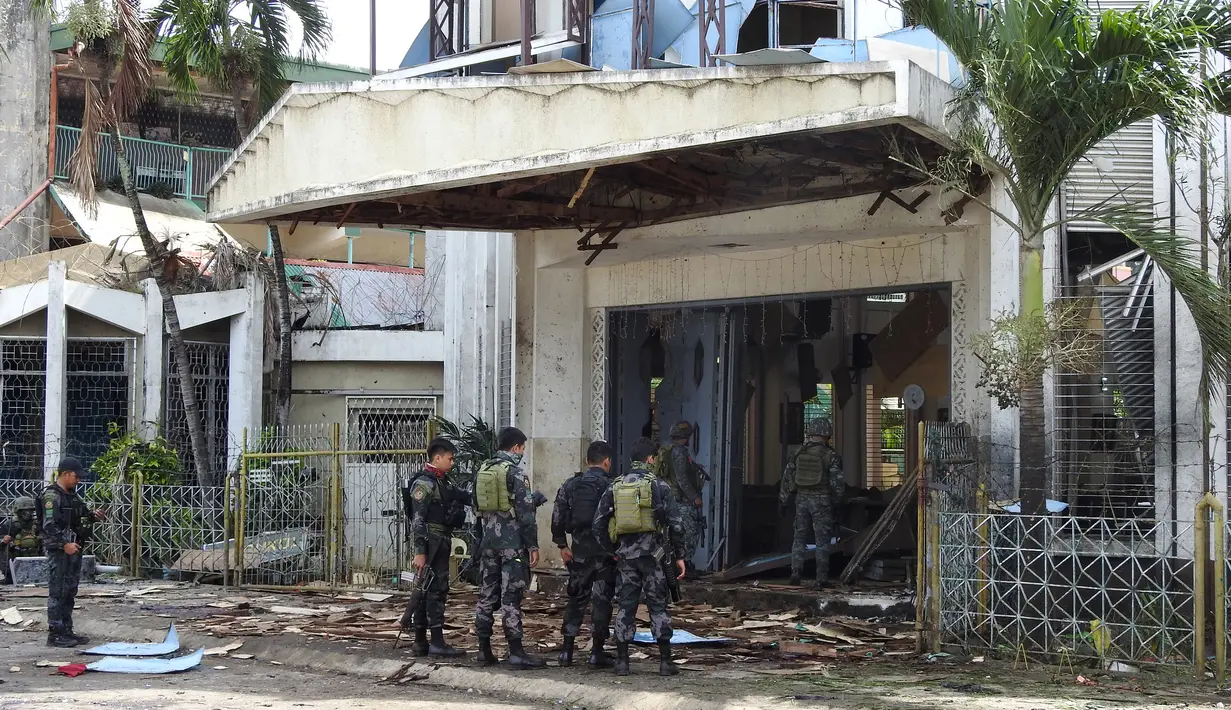 Polisi dan tentara berjaga pasca ledakan bom di Gereja Katolik Jolo, Filipina Selatan, Minggu (27/1). Dua bom meledak, Sedikitnya 27 orang tewas dan 57 orang lainnya mengalami luka. (Nickee Butlangan/AFP)