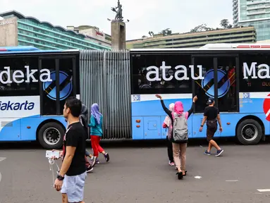 Sebuah bus TransJakarta koridor 1 dengan stiker bertuliskan Merdeka atau Macet melintas ketika masyarakat Jakarta tengah berolahraga saat Car Free Day (CFD) di kawasan Bundaran HI, Jakarta, (14/08). (Liputan6.com/Fery Pradolo).