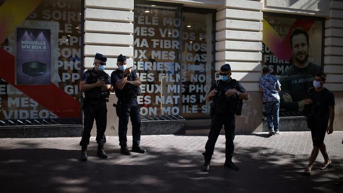 Polisi anti huru-hara Prancis mengamati warga yang mengenakan masker di Marseille, Selasa (18/8/2020). Pemerintah Prancis mengirim polisi anti huru hara ke wilayah Marseille untuk membantu menegakkan peraturan penggunaan masker saat negara itu mencatat lonjakan kasus COVID-19. (AP Photo/Daniel Cole)