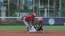 Pemain Indonesia, Hermansyah (kiri) mencoba mematikan langkah pemain Singapura pada laga Asian Softball Championship di Senayan, Jakarta,Selasa (25/4/2018). Indonesia menang atas Singapura 8-2. (Bola.com/Nick Hanoatubun)