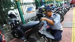 Petugas Dishub mengembosi motor yang parkir di sepanjang trotoar kawasan Kebon Sirih, Jakarta, Rabu (18/1). Puluhan motor diamankan serta digembosi dalam penertiban tersebut karena menutupi jalur pedestrian. (Liputan6.com/Immaniel Antonius)